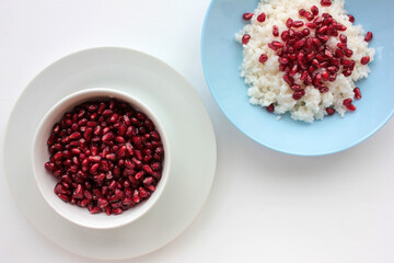 Middle eastern rice pilaf with raw pomegranate seeds in a blue bowl on white background. Flat lay food composition. Top view, copy space. 