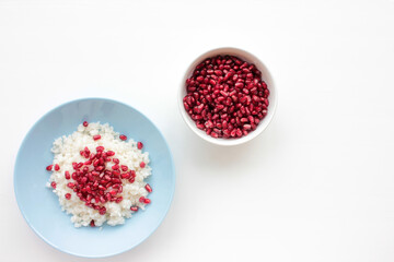 Middle eastern rice pilaf with raw pomegranate seeds in a blue bowl on white background. Flat lay...