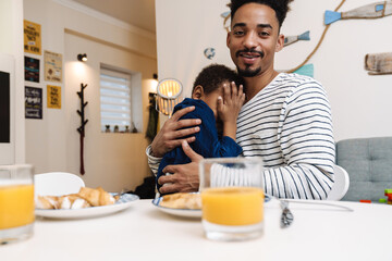 African american father and son hugging while having breakfast