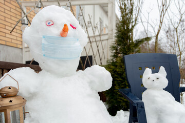 In the courtyard of the house there is a snowman in a medical mask.
Concept, spring, protect...