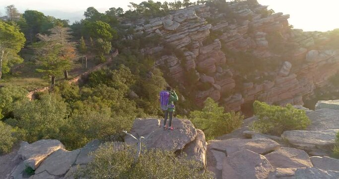 Mujer senderista con mochila y abrigo haciendo fotograf&iacute;as a valle al amanecer