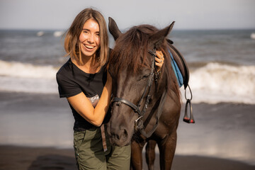 Obraz premium Portrait of happy woman and brown horse. Young Caucasian woman hugging horse. Romantic concept. Love to animals. Nature concept. Bali