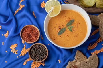 A white bowl of lentil soup with spices and bread