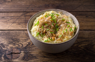 Traditional Irish dish colcannon, mashed potatoes with cabbage and green onions, on top of crispy fried cabbage topping with nuts and spices on wooden table