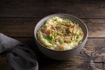 Traditional Irish dish colcannon, mashed potatoes with cabbage and green onions, on top of crispy fried cabbage topping with nuts and spices on wooden table