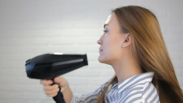 A young woman dries her hair with a hair dryer. Soft selective focus. Red hair