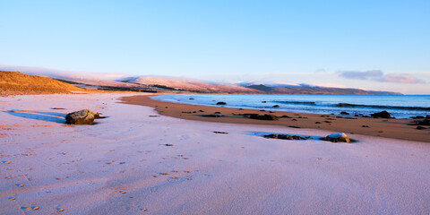 Brora beach in the Highlands in winter with snow on the sand and on the hills