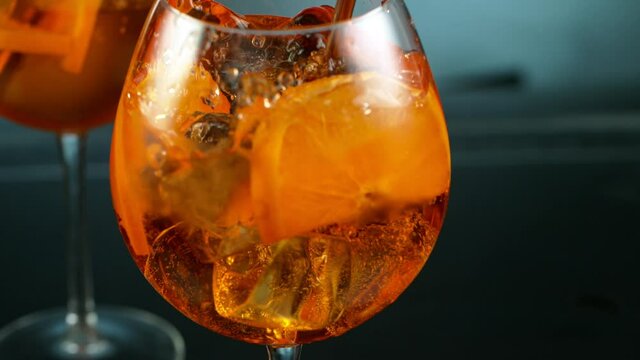 Ice cube falling into glass of orange cocktail. Aperol spritz
