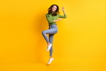 Fototapeta na wymiar Full length photo of attractive happy joyful woman wear jeans jump up dance enjoy isolated on yellow color background