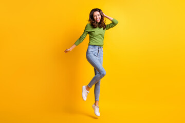 Full size photo of joyful cheerful pretty woman jump up air touch hair isolated on shine bright yellow color background