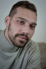 Obraz premium Portrait of a young brown-haired man with a short beard and a gray turtleneck sweater