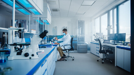 Modern Medical Research Laboratory: Scientist Wearing Face Mask Working with Pipette, Analysing Microbiological Sample. Advanced Scientific Lab for Drugs, Microbiology Development. High-Tech Equipment
