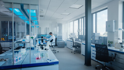 Modern Medical Research Laboratory: Caucasian Male Scientist Wearing Face Mask Working with...