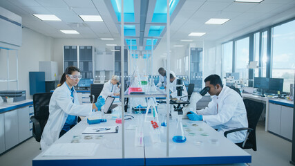 Modern Medical Research Laboratory: Diverse Team of Scientists Working Using Microscope, Analysing...