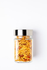 Spicy Chatpata Mixture in a glass jar with a closed lid, made with peanuts, corn flakes. Indian spicy snacks (Namkeen), Top view, over white background.