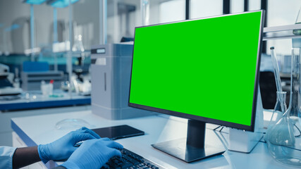 Modern Medical Research Laboratory: Scientist working on Computer Showing Green Chroma Key Screen. Scientific Lab, Medicine Development Facility with Advanced Equipment, Biotechnology.