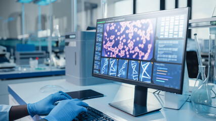 Modern Medical Research Laboratory: Portrait of Male Scientist working on Computer Showing DNA concept. Scientific Lab and Medicine Development Facility with Advanced Equipment, Biotechnology.