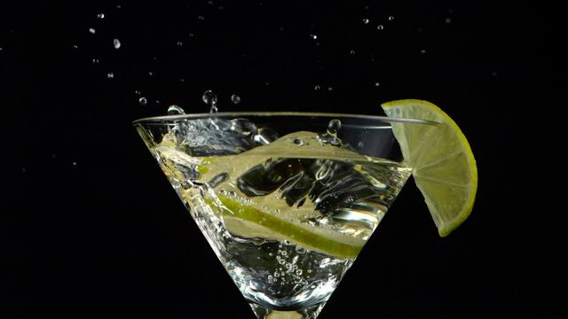 Camera Motion. Bright Cocktail with Falling Lime on Dark Background. Super Slow Motion.