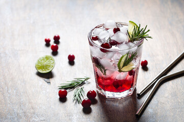Refreshing cranberry drink with ice, lime and fresh rosemary