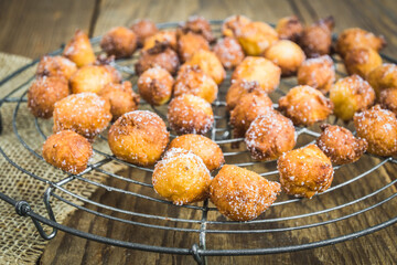 Homemade Castagnole, Mutzen or Castagnole, typical german or italian carnival fritters with sugar on a cooling rack