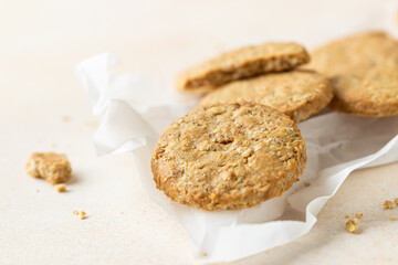 Healthy oatmeal or multigrain cookies with seeds and nuts on baking paper, light concrete background.