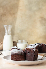 Chocolate sponge flourless cake with sugar powder, light concrete background. Brownie cake. Toned image.
