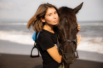 Fototapeta premium Portrait of charming woman and brown horse. Young Caucasian woman hugging horse. Romantic concept. Love to animals. Nature concept. Bali