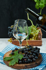 Plate of various grapes and a glass of wine on white table with wine bottle
