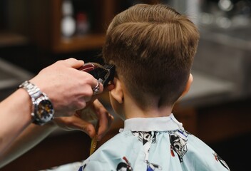 Cheerful Caucasian boy getting hairstyle in barbershop.