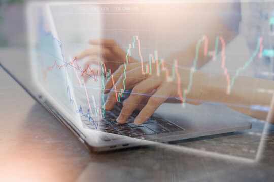 ノートPCを操作する女性の手と株価チャートの合成写真