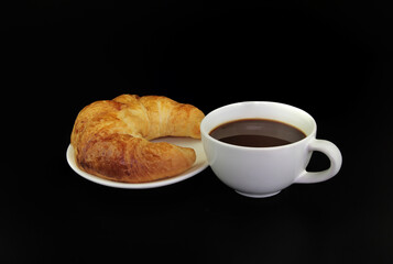 Croissants on a plate with a cup of espresso coffee isolated on black background