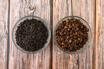 Tea leaves for infuser and roasted coffee grains packaged in cups on a wooden table