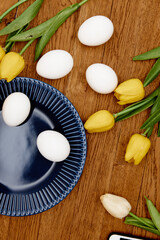 blue plate of chicken eggs yellow tulips decoration holiday