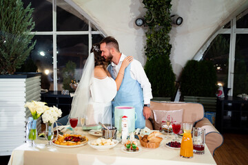newlyweds kiss and hug in restaurant and listen to congratulations from guests.