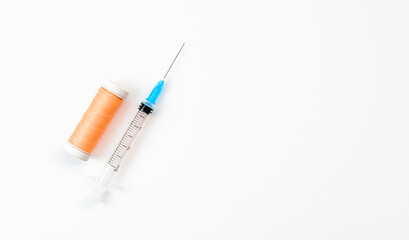 Syringe with threads on white background. The concept of surgery and wound stitching.