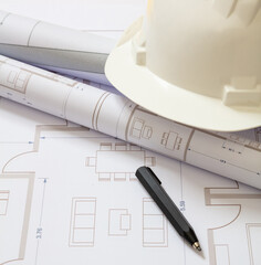 Construction concept. Residential building drawings and hardhat on an office desk