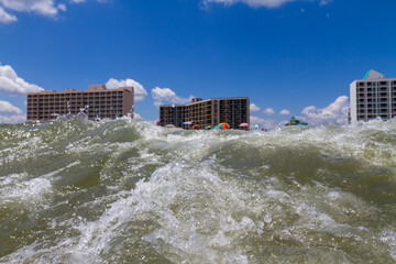 High ocean waves of water approach the beach populated during vacation
