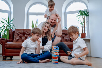 Warm portrait of joyful family of mother and father with their children they play tower challenge game together.