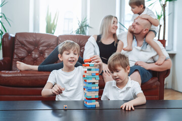 Warm portrait of loving and happy family at home. Boys play board game and enjoying their holidays together in living room.