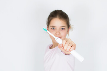 Young caucasian girl holding and showing sonic electric toothbrush isolated on white background....