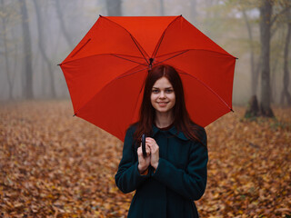 Woman with red umbrella in the park in autumn Yellow leaves walk the fog
