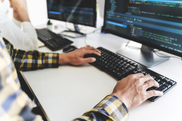 programmer writing program code with two monitors and working on a new software or hacker...