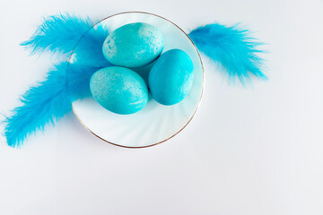Composition of blue easter eggs and feathers on a light background.