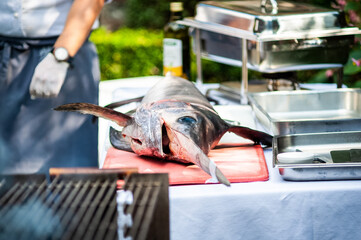 whole swordfish ready to be cut by the cook - grilled swordfish outdoors during a wedding party