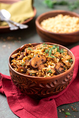 Spicy bulgur with mushrooms, onions, dill, and cumin in a bowl close-up. Bulgur stewed with mushrooms. Arabic cuisine, vegan and vegetarian food.