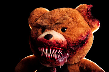 scary bear with a creepy bloody grin on a black background. horror toy. halloween concept. a...