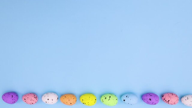 Easter eggs different colors passing on bottom of paste blue theme. Stop motion