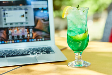 A fruit lemonade next to laptop on wooden table