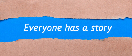 A strip of blue paper with the words EVERYONE HAS A STORY between the brown paper. View from above