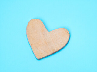 Wooden hand made heart on flat blue background